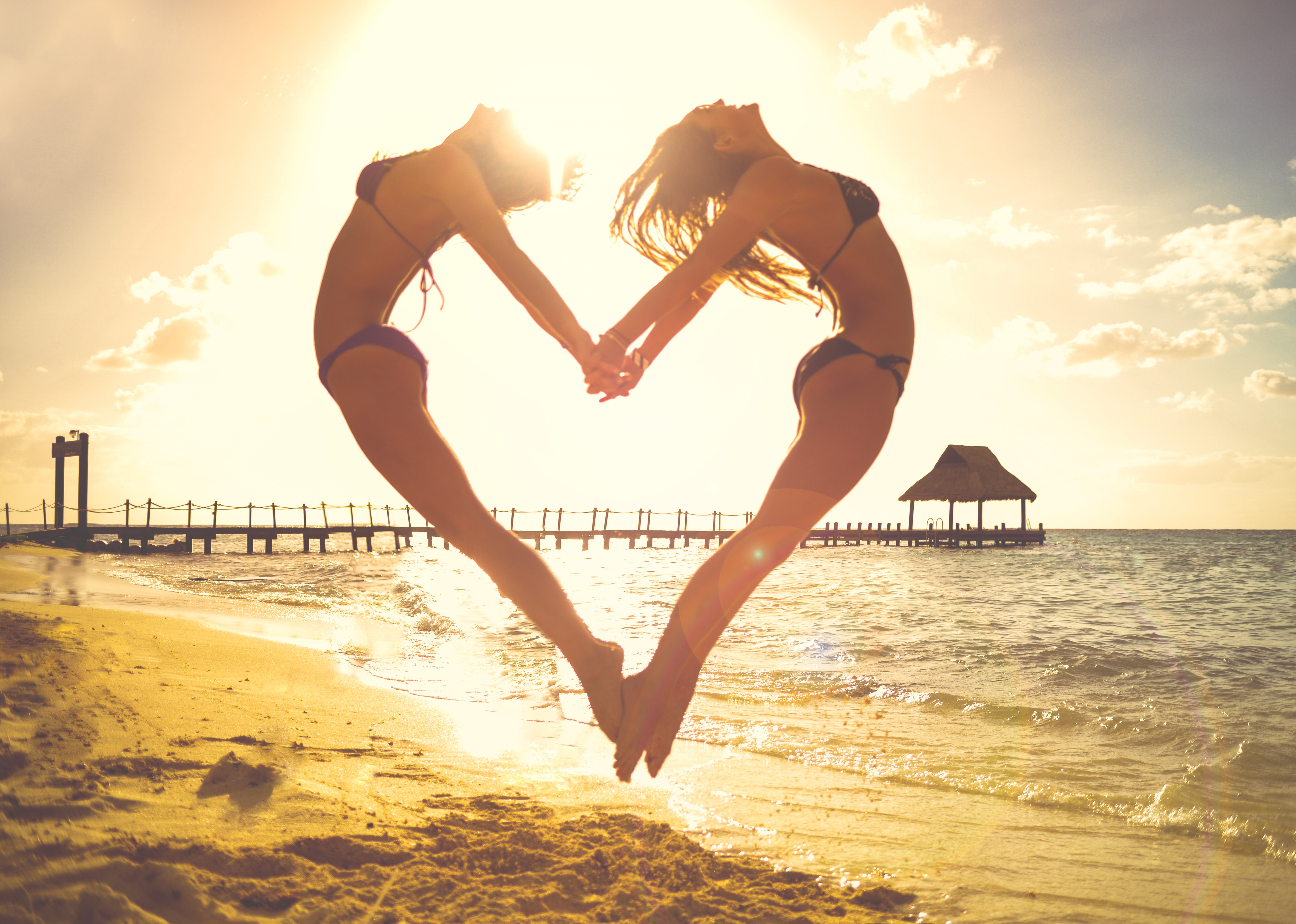 Gilrs On Beach Jumping To Make Cute Love Heart